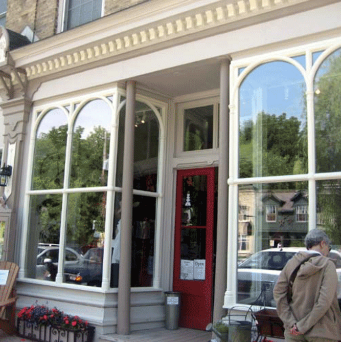 A storefront in Bayfield Ontario featuring curved window mouldings and a red door